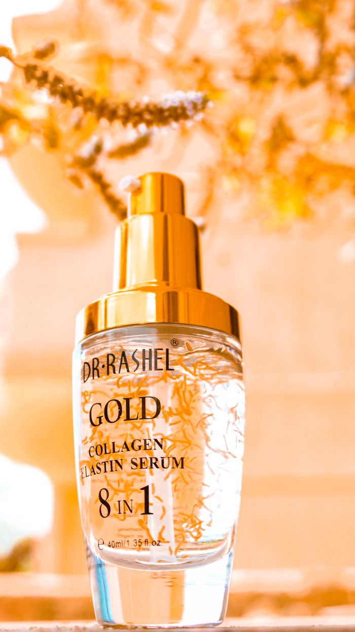 about-us-01 Close-up of a luxury gold collagen serum bottle in a natural, golden setting.